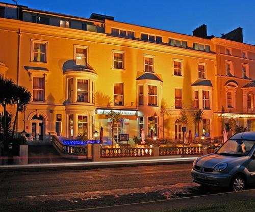a car parked in front of a large yellow building at Tynedale Hotel in Llandudno