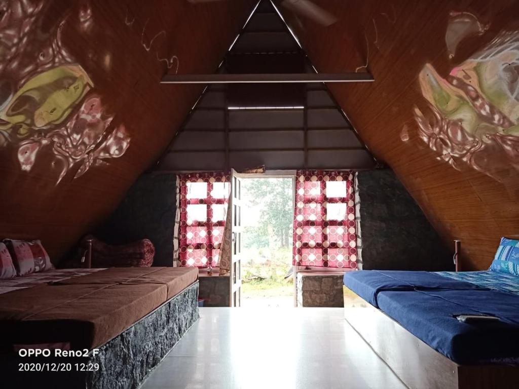 a attic room with two beds and a window at John home stay in Yelagiri