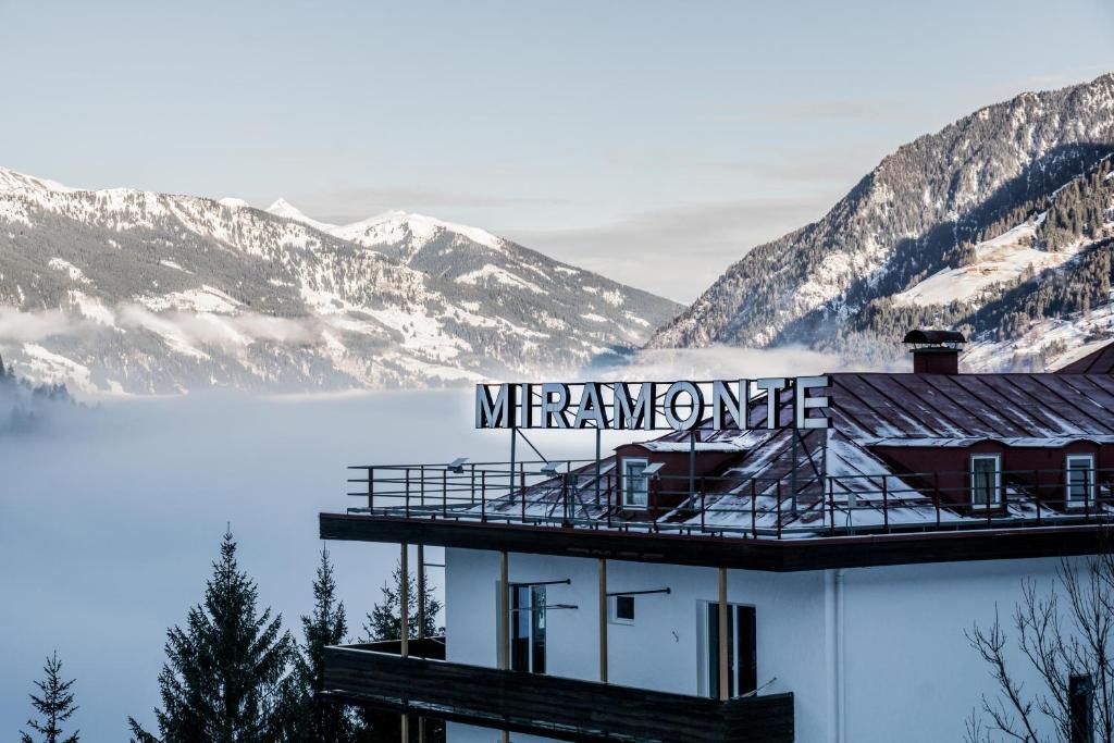 un edificio con un cartello in cima con delle montagne di Design Hotel Miramonte a Bad Gastein