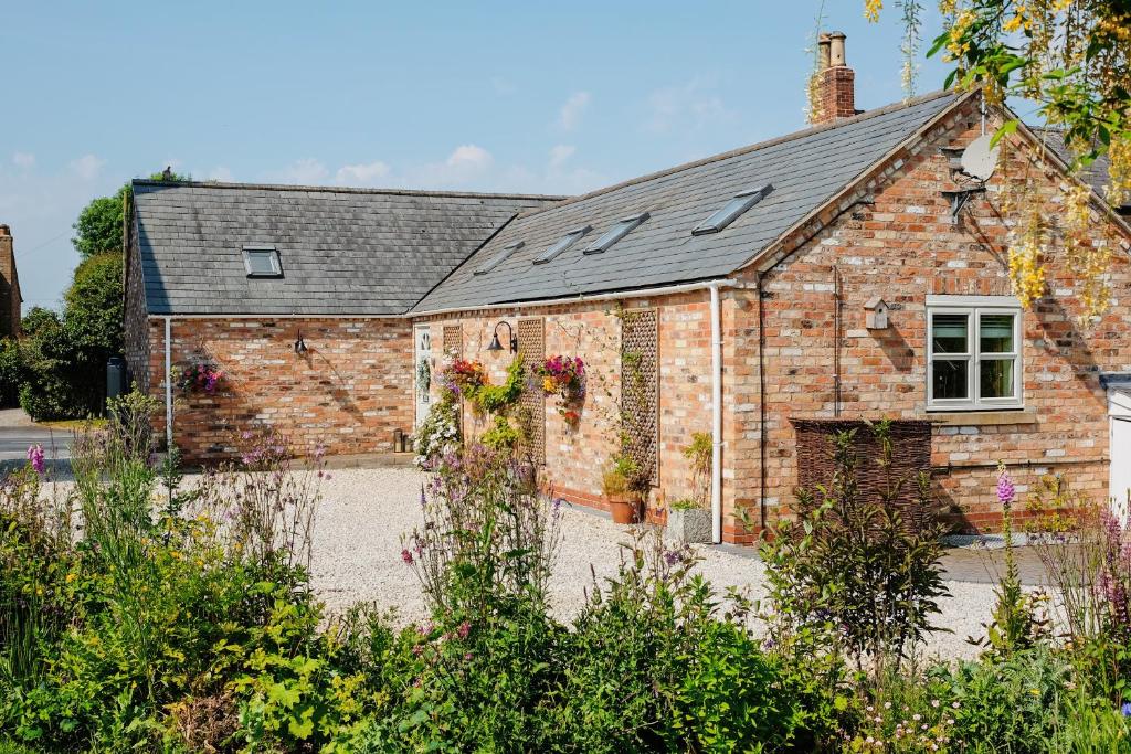 una vieja casa de ladrillo con flores. en Little Lodge on the Yorkshire Wolds en York