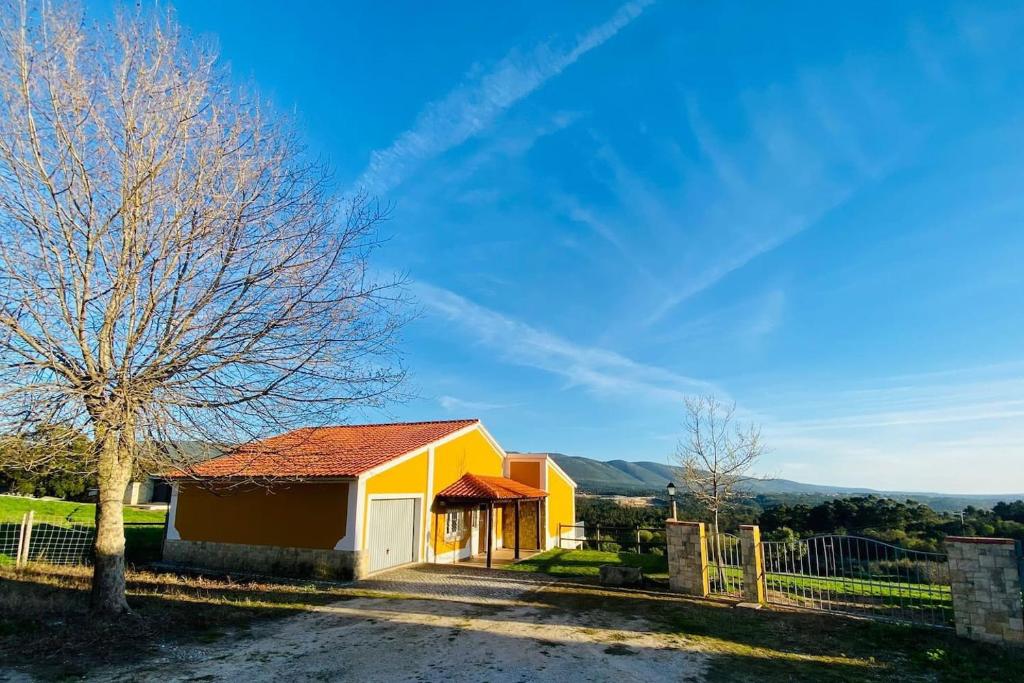 una casa gialla con un albero e una recinzione di Casa De Campo Natureza a Porto de Mós
