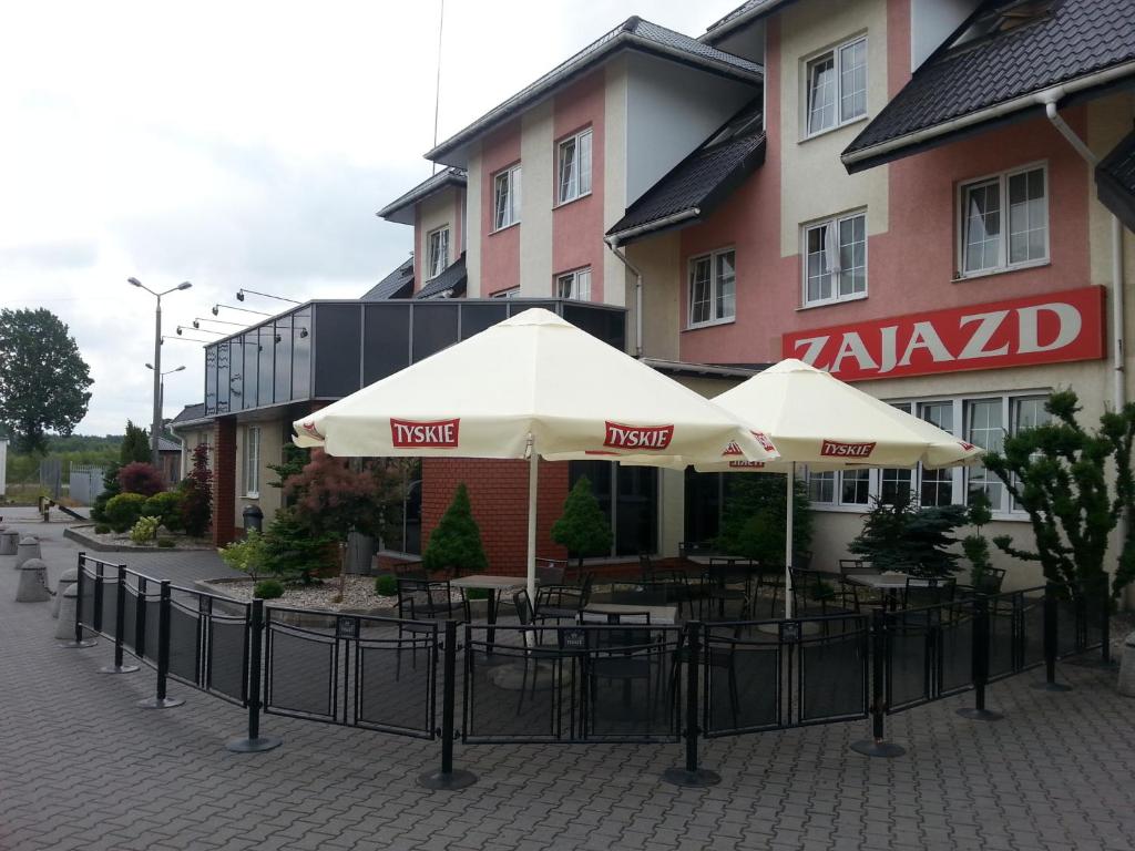 un restaurante con mesas y sombrillas frente a un edificio en Max na terenie stacji MOL, en Radzymin