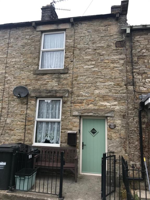a brick house with a green door and windows at Cherry Tree Cottage, Aysgarth in Leyburn