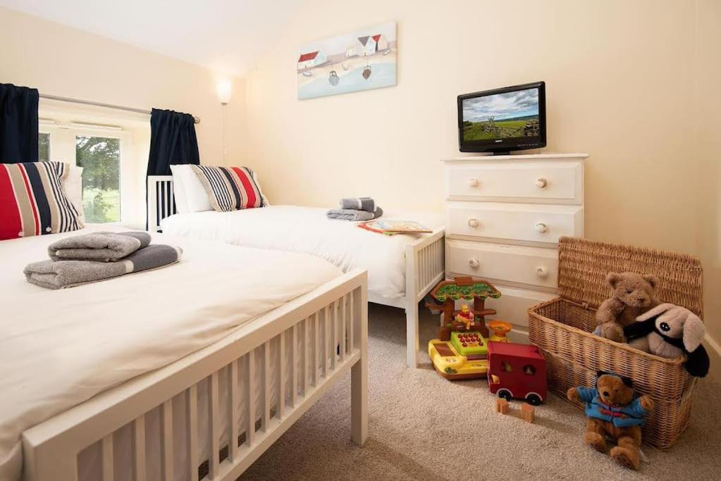 a bedroom with two beds and a crib and toys at Sandpiper Cottage in Alnham