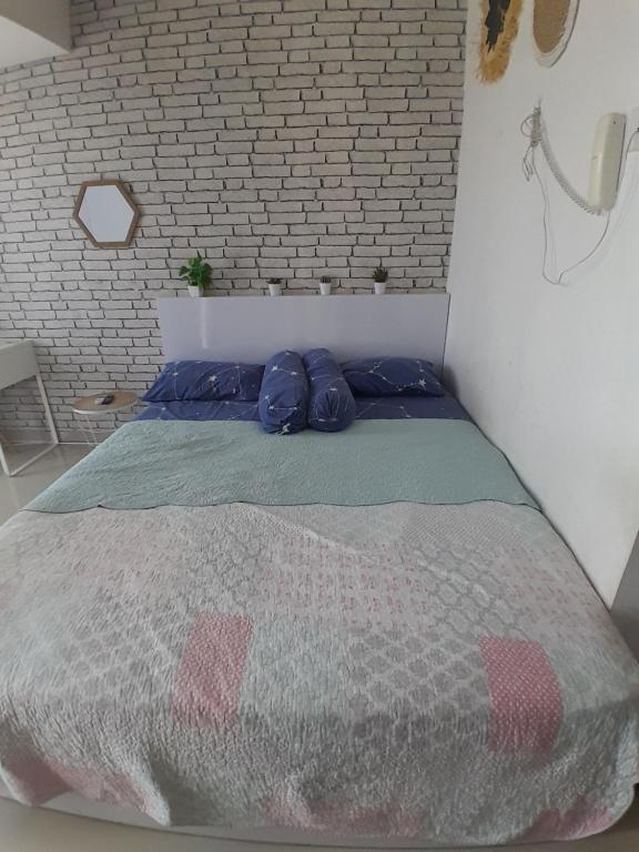 uma cama num quarto com uma parede de tijolos em Niatmy em Kejayan