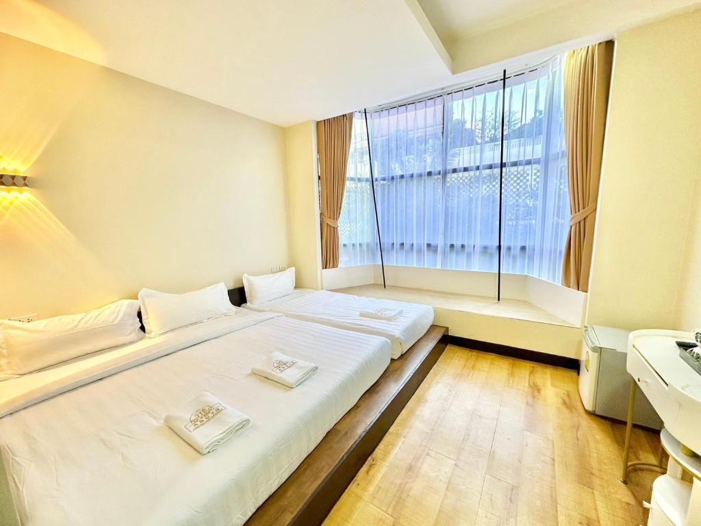 um quarto com 2 camas e uma grande janela em ABC SO Hotel Bangkok em Bangkok