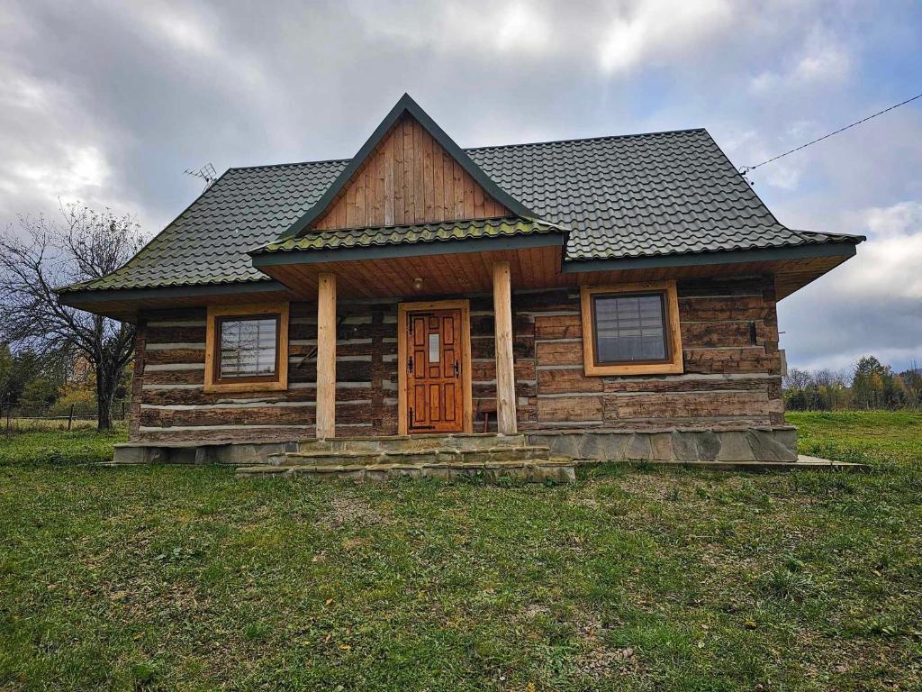 a log cabin with a wooden door in a field at Serce Beskidu Niskiego Myscowa in Krempna