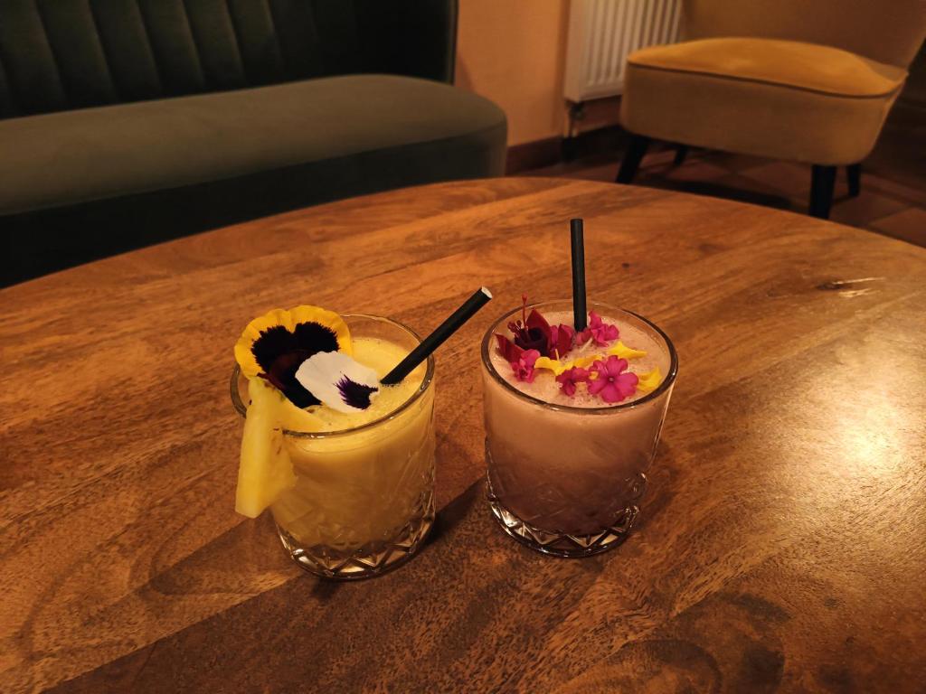 two cocktails sitting on a wooden table at Hôtel La Reconce in Poisson