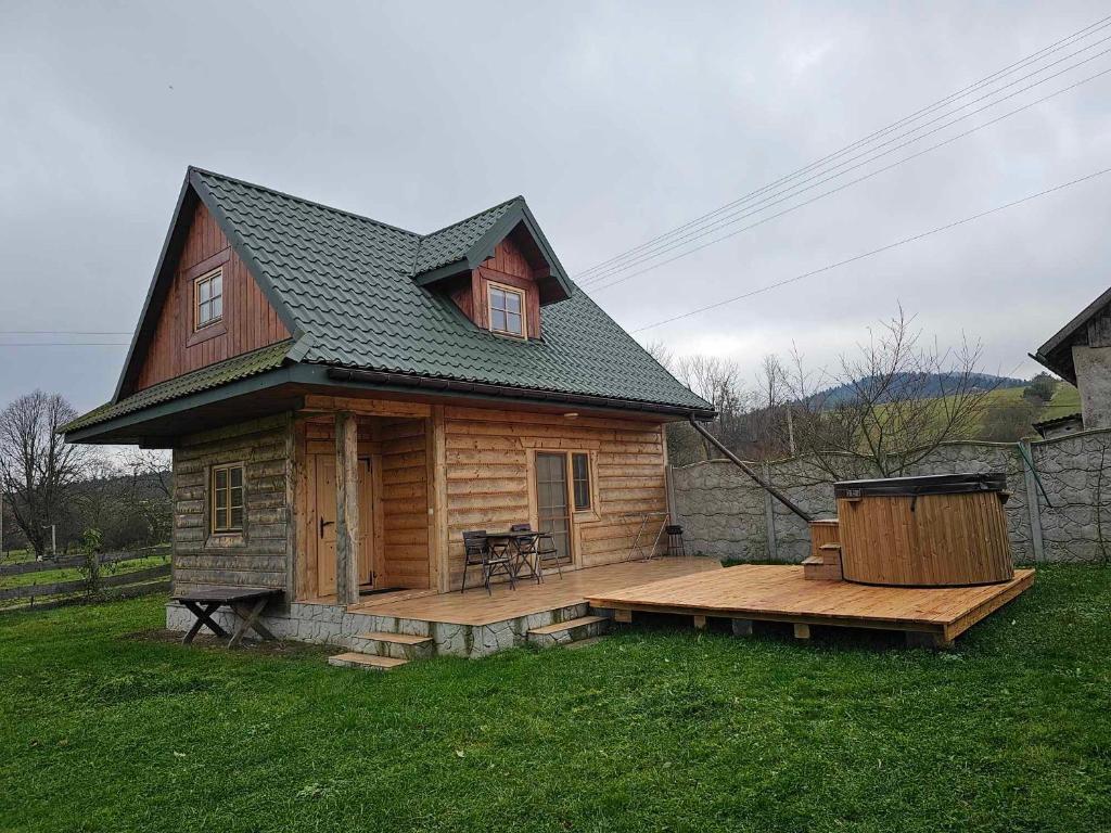 a log cabin with a deck in the yard at Serce Beskidu Niskiego in Świątkowa Mała