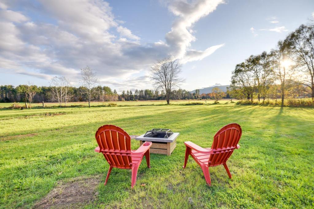 duas cadeiras vermelhas sentadas ao lado de uma grelha num campo em Farmview Duplex about 2 Mi to Newfound Lake! 