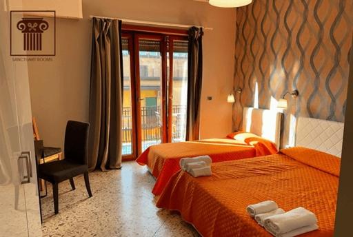 una camera d'albergo con due letti e una sedia di Sanctuary Rooms a Pompei