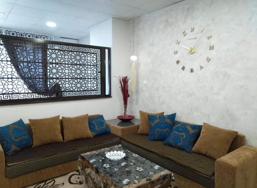 a living room with a couch and a clock on the wall at Luxe Studio Sea View in Oran