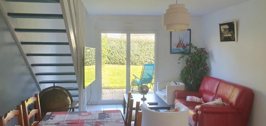 a living room with a red couch and a table at Maison proche bourg, à 5 min des plages en voiture, 10 minutes de Larmor Plage, Lorient et Guidel Plages in Ploemeur