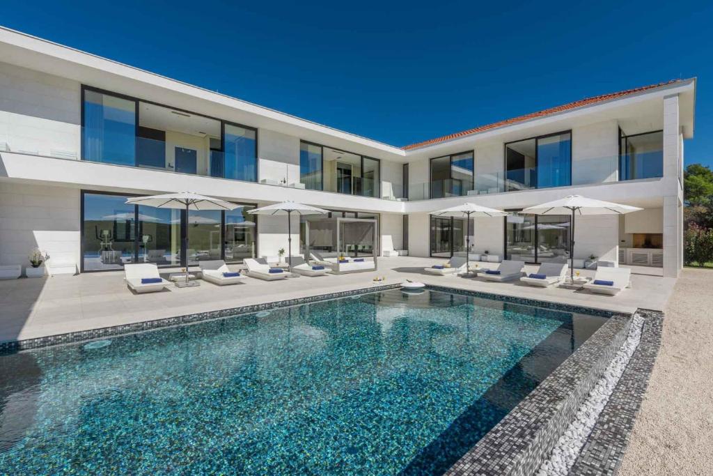 una casa con piscina frente a ella en Villa Vrsar Magnifique A Beautiful Contemporary 5 Bedroom Villa Sauna and Gym, en Vrsar