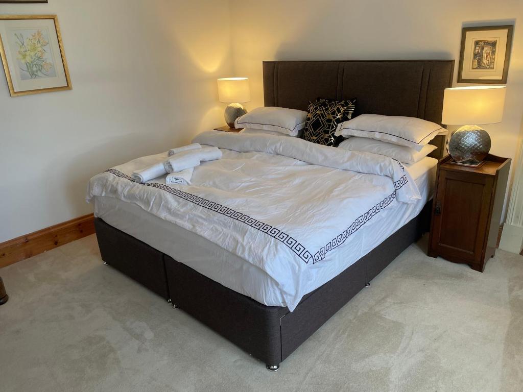 um quarto com uma cama grande com lençóis brancos e almofadas em Brackfield House Deal 49 em Killaloo