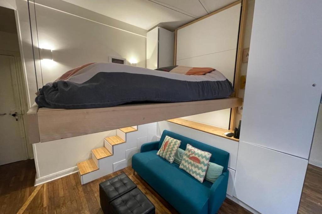 a small bedroom with a bed and a blue couch at Lovely love nest near Paris in Clichy