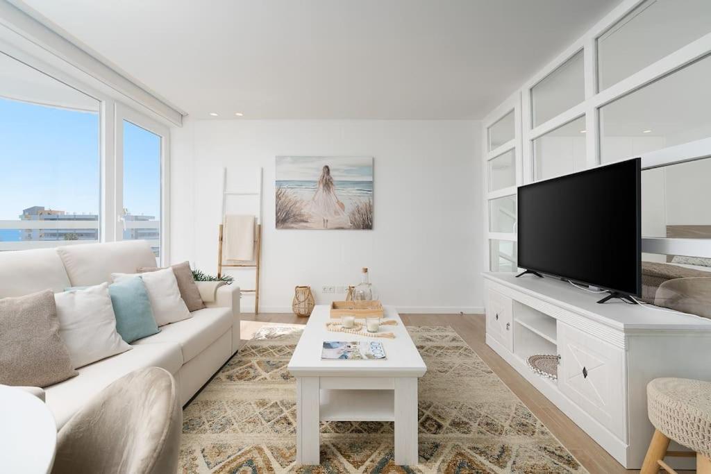 ein Wohnzimmer mit einem weißen Sofa und einem Flachbild-TV in der Unterkunft Stylish Beachfront Escape . Steps to Beach . Wifi in Portimão