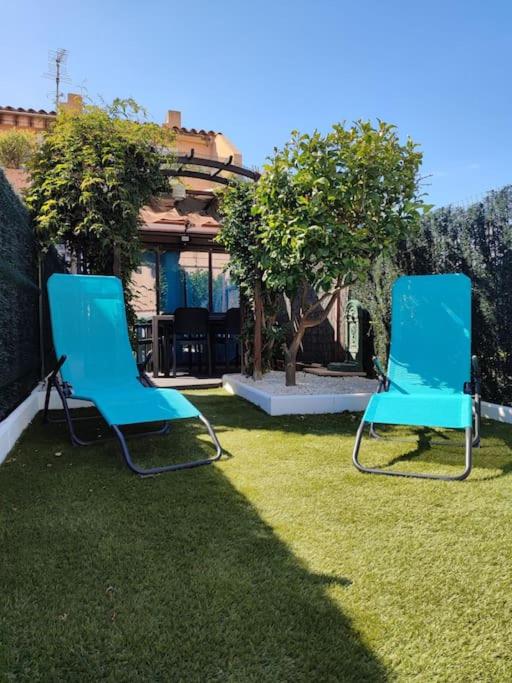 dos sillas azules sentadas en el césped en un patio en superbe appartement proche du port et de la plage., en La Londe-les-Maures