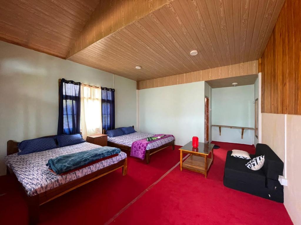 a bedroom with two beds and a red carpet at Kolakham Hillcrest Homestay in Rishop