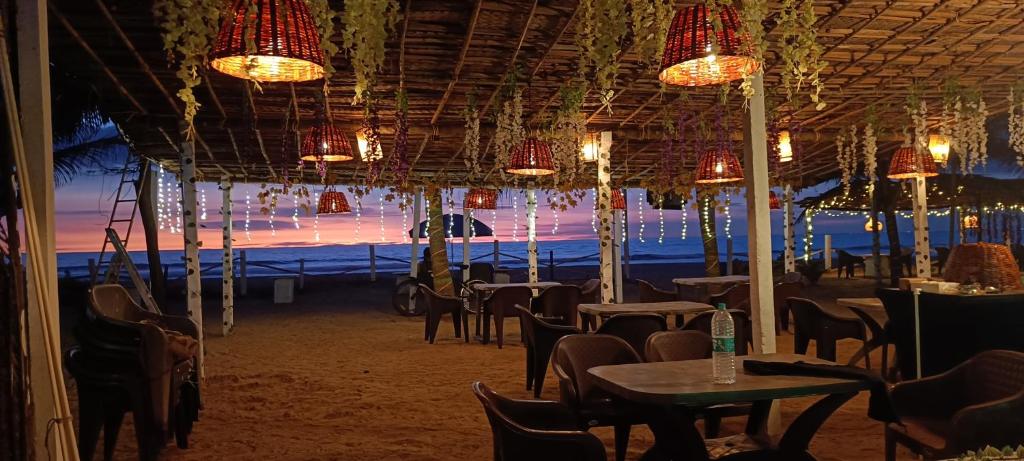 uma sala de jantar com mesas, cadeiras e luzes em Gokarnastops Cafe & Stay for Backpackers em Gokarna