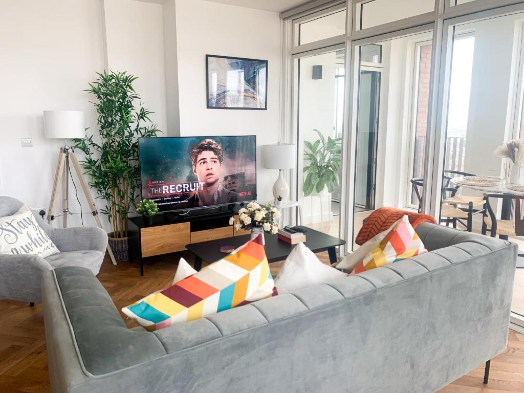 a living room with a grey couch and a tv at Luxurious two-bedroom flat with scenic views in London