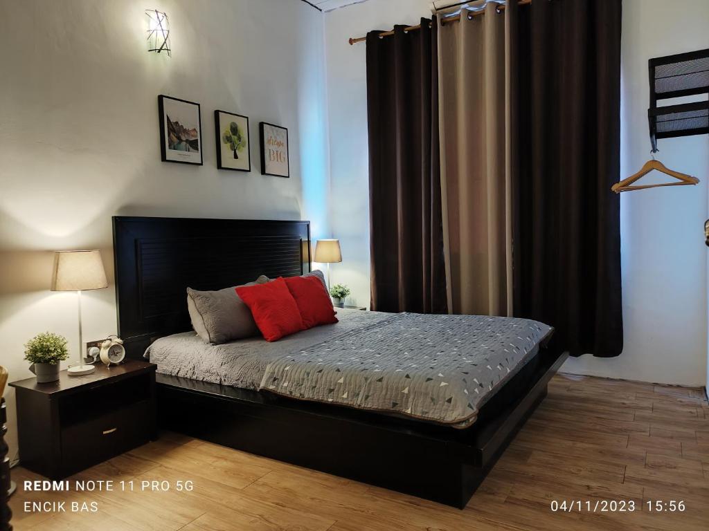 1 dormitorio con cama negra y almohada roja en Basrie Homestay Pagoh - Private Pool/W-ifi/NetFlix/Cozy en Pagoh