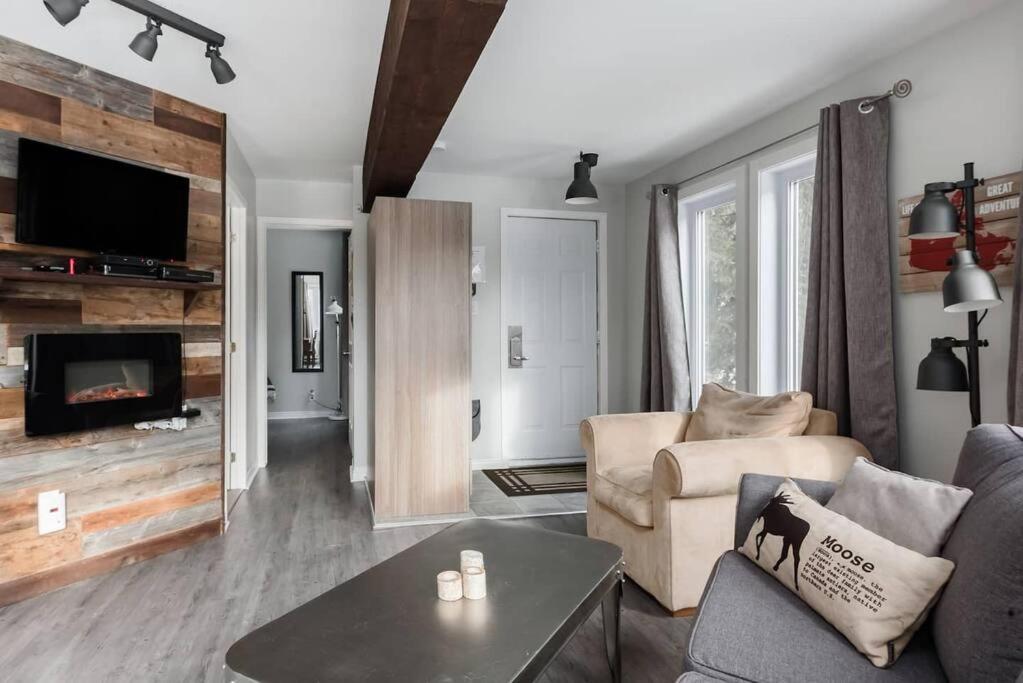 Chouette A - Mont-Tremblant في مونت تريمبلانت: غرفة معيشة مع أريكة ومدفأة