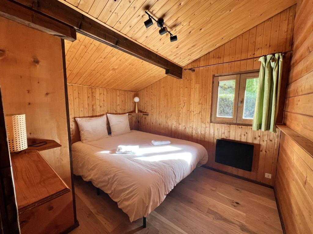 een slaapkamer met een bed in een houten hut bij Chalet Mouflon - Vue lac imprenable in Thollon