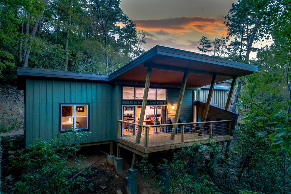 ein grünes Haus mit einer Terrasse im Wald in der Unterkunft Pilot Cove in Pisgah Forest