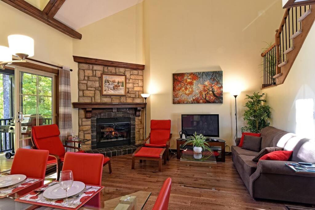 a living room with red chairs and a fireplace at Manoir B - Mont-Tremblant in Mont-Tremblant