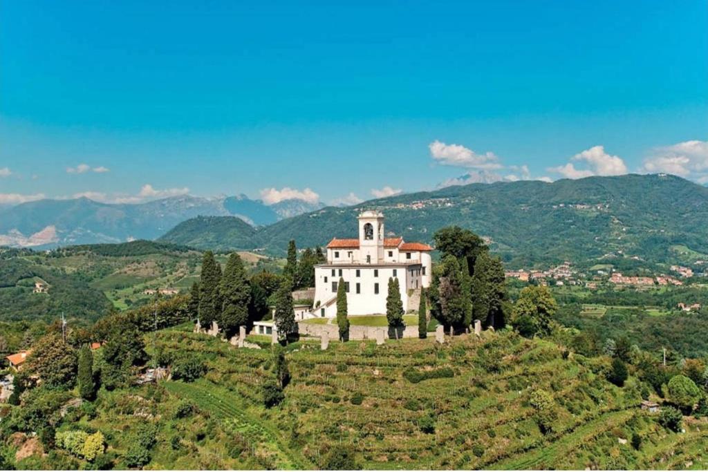 un grand bâtiment blanc sur une colline plantée d'arbres dans l'établissement 039 Maggioni B&B, à Montevecchia