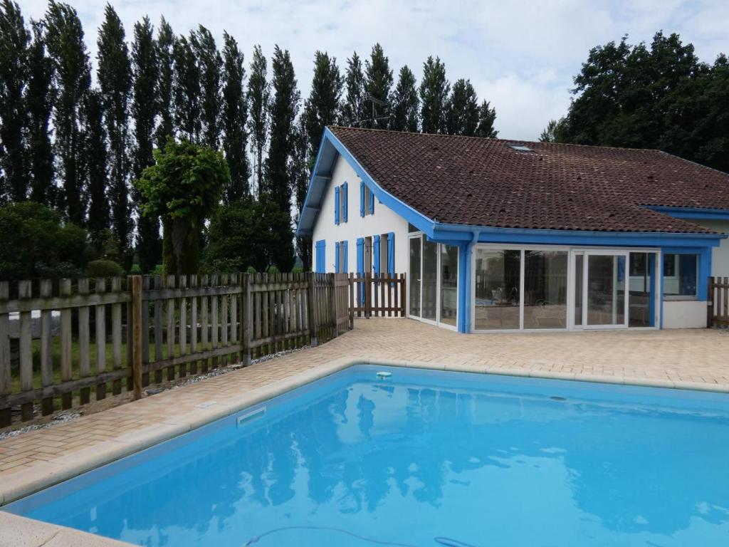 a house with a blue swimming pool in front of a fence at Le grand bidot in Louer