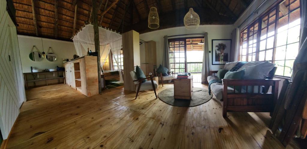 a living room with wood floors and a couch at Amare Cabin in the bush with all your needs! in Marloth Park