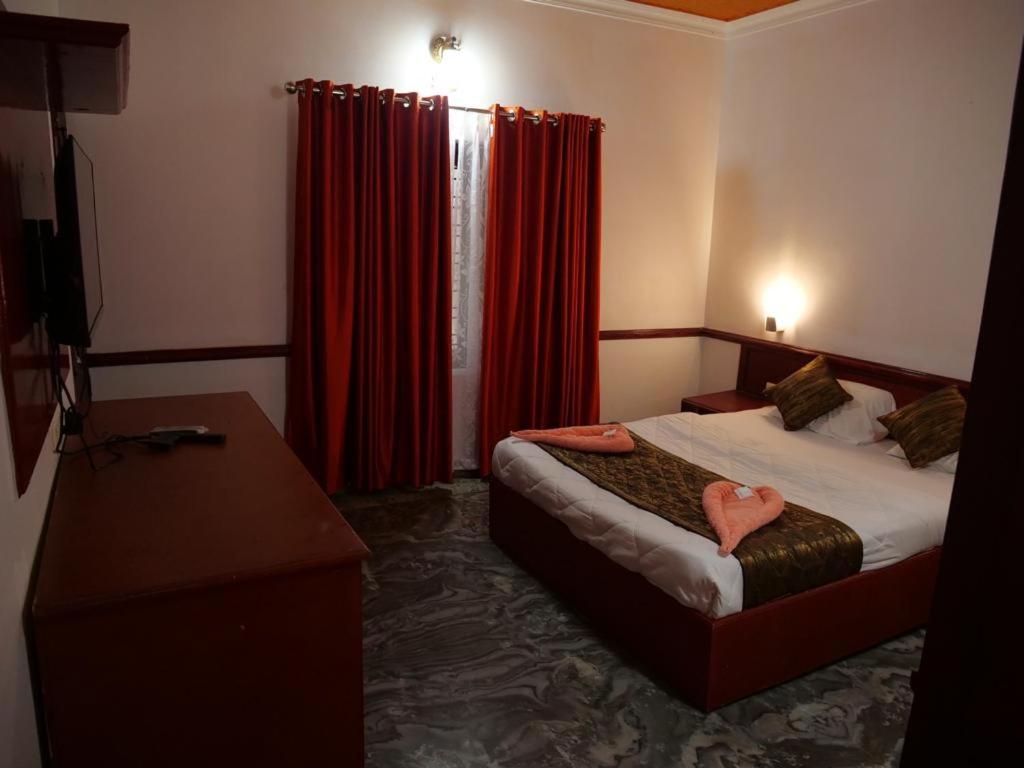 ein Hotelzimmer mit einem Bett und roten Vorhängen in der Unterkunft Hosteller's in Varkala