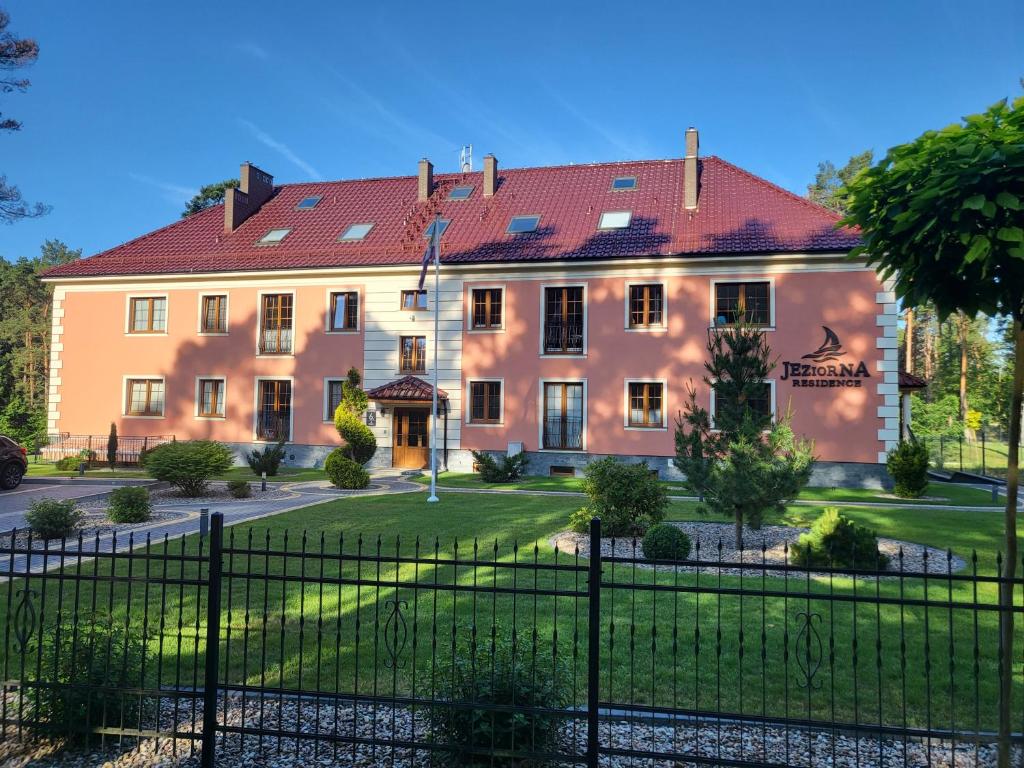 duży budynek z płotem przed nim w obiekcie APARTAMENT przy jeziorze w Bornem-Sulinowie