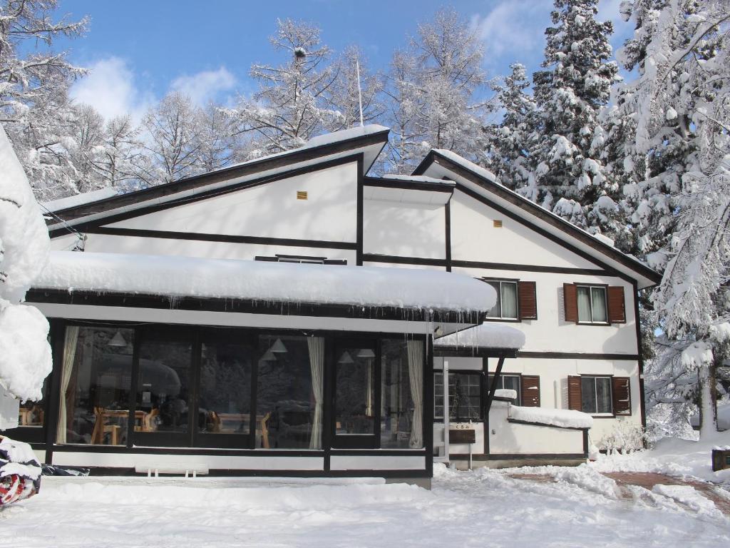 uma casa na neve com árvores cobertas de neve em Hakuba Goryu Pension Kurumi em Hakuba