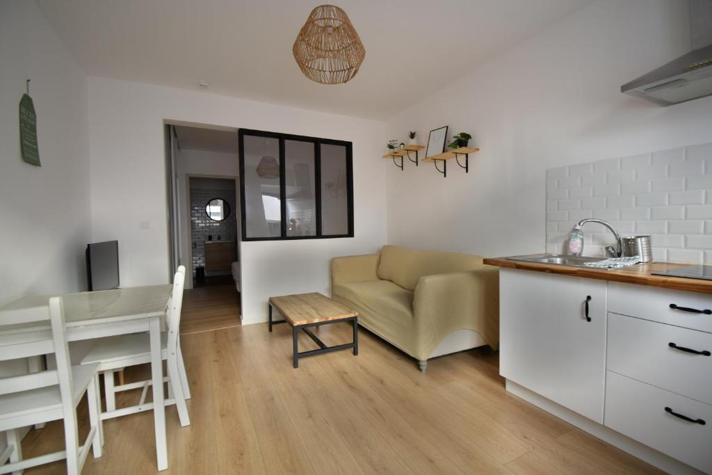 een keuken en een woonkamer met een bank en een tafel bij Appartement cosy à 50 m de la plage et du port in Mèze