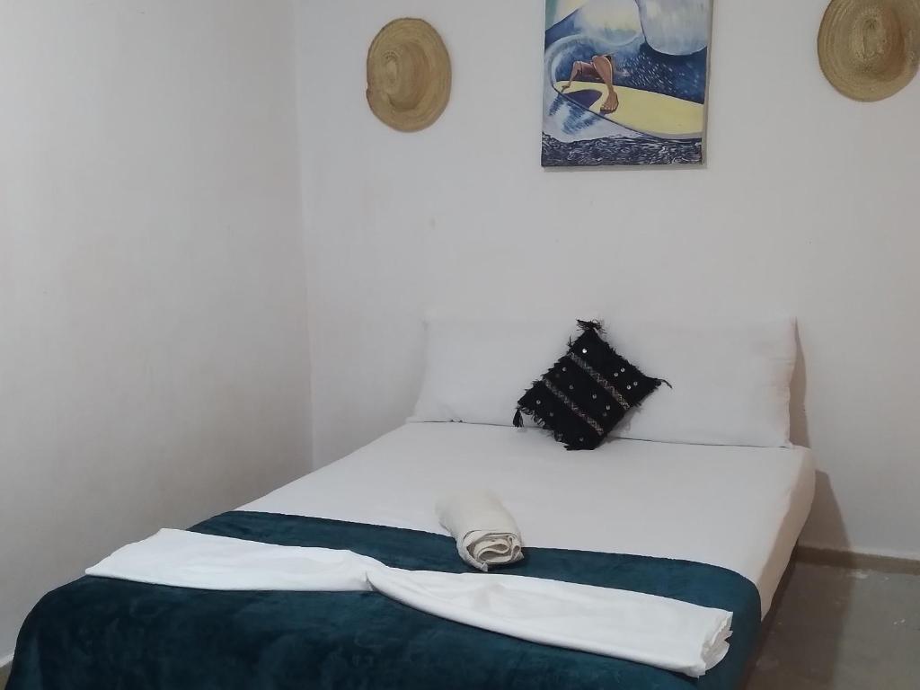 - une chambre avec un lit blanc et une couverture bleue dans l'établissement Idriss's hostel, à Taghazout