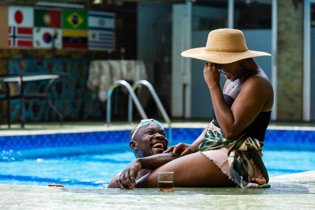 Una donna che parla al cellulare vicino a un uomo in piscina di Charleston Hotel a Accra