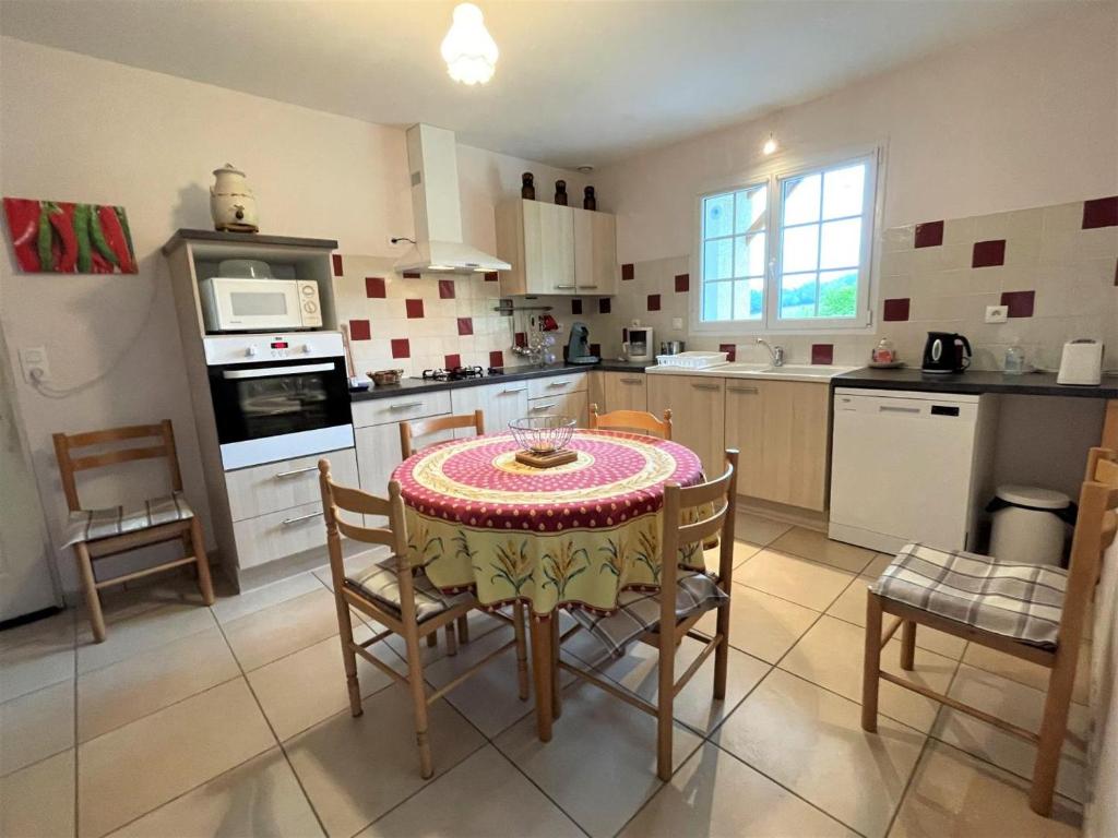 a kitchen with a table and chairs in a kitchen at Chez estecahandy in Esquiule