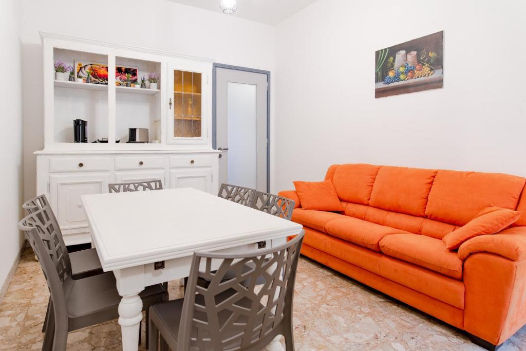Student's Home في تورينو: غرفة معيشة مع أريكة برتقالية وطاولة