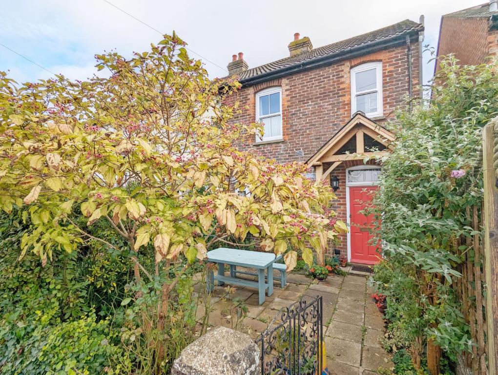 una casa con una puerta roja y un banco azul en Thorney Road, en Emsworth