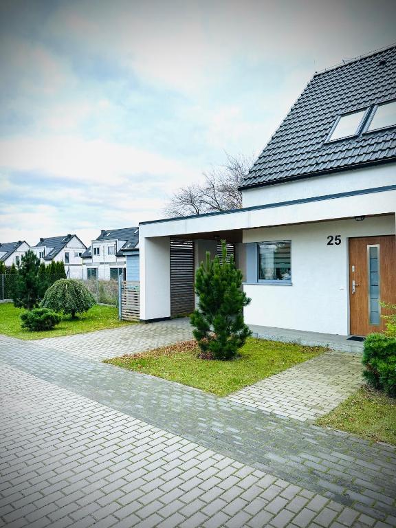 a white house with a driveway at Coast House 25 -BALTIC GARDEN TRZĘSACZ in Trzęsacz