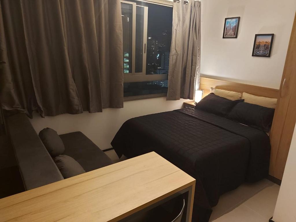 um pequeno quarto com uma cama e uma janela em Flat / Studio Allianz Parque em São Paulo