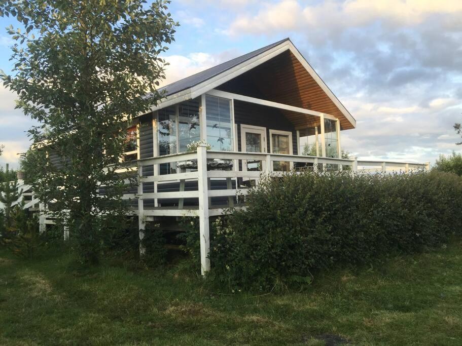 ein kleines Haus mit Glasfenstern auf einem Feld in der Unterkunft Golden Circle Cozy Retreat in Grímsnes og Grafningshreppur