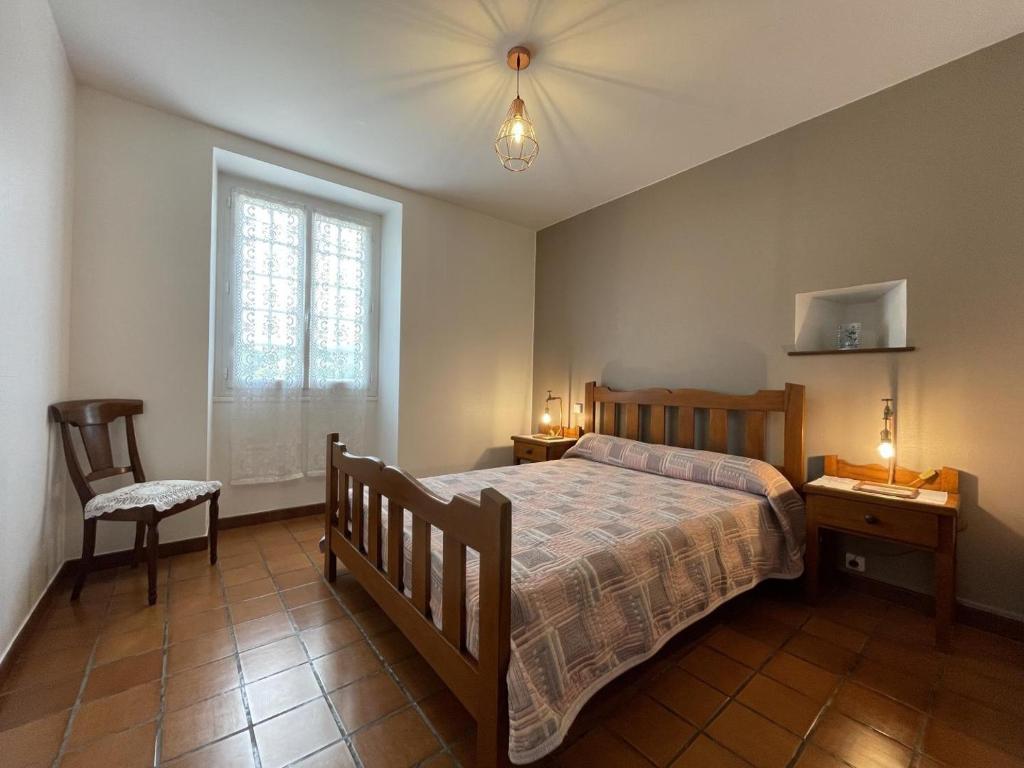 a bedroom with a bed and a chair and a window at Barrukia in Uhart-Cize