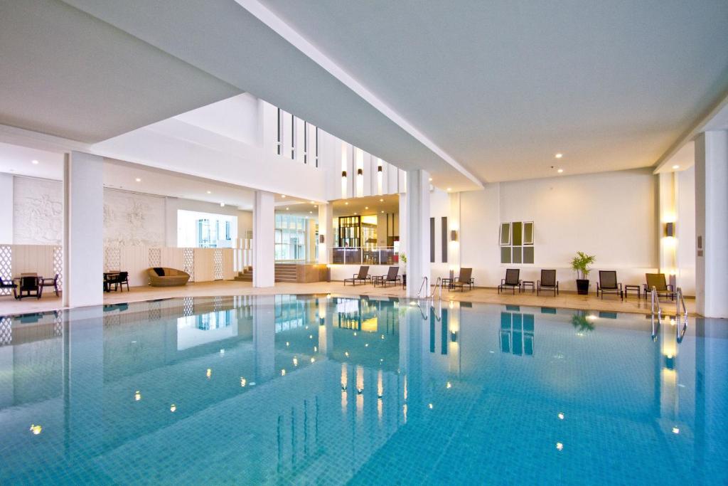 a large swimming pool with blue water in a building at Classic Kameo Hotel & Serviced Apartment, Rayong in Rayong