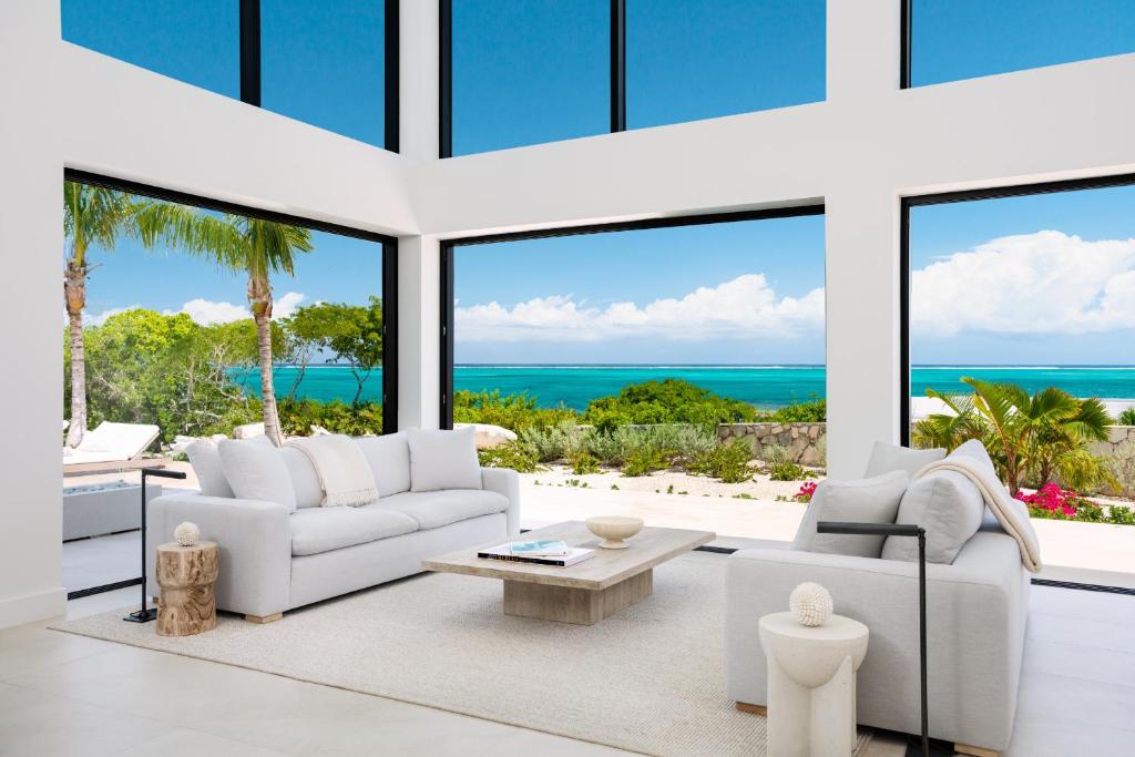 a living room with white furniture and large windows at Beachwood Villa in Turtle Cove