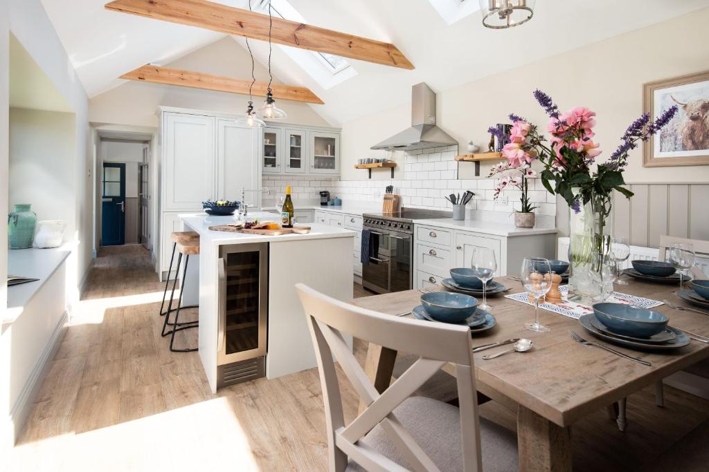 a kitchen with a wooden table and a dining room at Overview Cottage in Belford