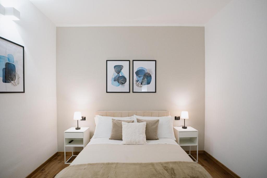 een witte slaapkamer met een groot bed met drie foto's aan de muur bij Alatea Apartments Poloni in Verona